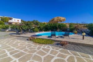 a swimming pool with chairs and an umbrella at Villa Nastazia in Kiotari +26 photos