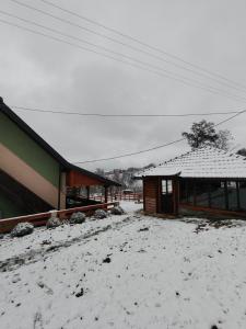 a house with snow on the ground next to a building at Kuca za odmor ViP in Kremna