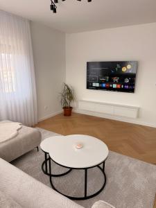 a living room with a table and a tv on a wall at Apartman Sara in Posušje