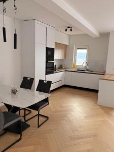 a kitchen with white cabinets and a table and chairs at Apartman Sara in Posušje