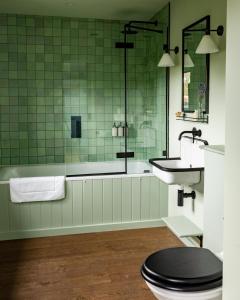 a bathroom with a toilet and a sink and a tub at The Merry Harriers Pub in Hambledon