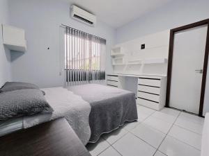 a white bedroom with a bed and a window at Casa de praia in São Luís