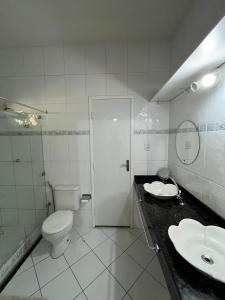 a white bathroom with a toilet and a sink at Casa de praia in São Luís