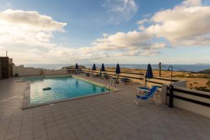 a swimming pool with chairs and umbrellas on a building at Agriturismo Finagliosu in Palmadula