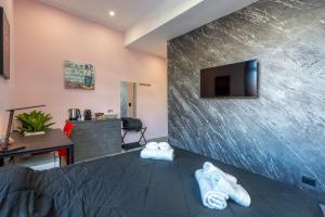 a room with a tv on a wall with two towels at Seashell Luxury Rooms Sanremo in Sanremo
