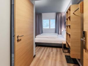 a small bedroom with a bed and a window at B&B HOTEL Mittenwald in Mittenwald