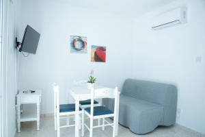 a room with a table and a chair and a tv at Flisvos Beach Apartments in Protaras +41 photos