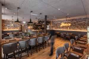 a person walking through a restaurant with tables and chairs at Smarthotel Schmid - Restaurant & Bar inhouse - Nähe Schlossteich in Sitzenberg