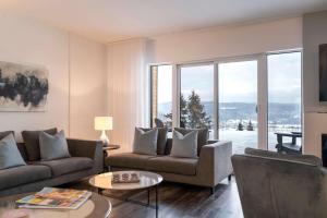 a living room with couches and a large window at Chic Condo - River View & Comfort with Pool in Baie-Saint-Paul +55 photos