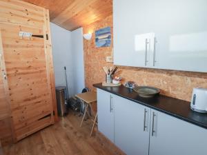 a kitchen with white cabinets and a wooden door at Rhosgranog Shepherds Hut in Haverfordwest