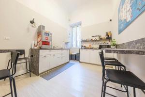 a large kitchen with white cabinets and black chairs at Il galleone in Messina