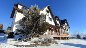 a large building with a tree in the snow at Gościniec Pieniński in Kluszkowce
