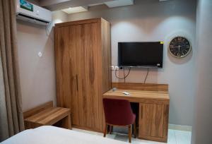 a bedroom with a desk with a tv and a cabinet at Yankers Royal Hôtel Kinshasa in Kinshasa