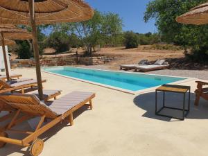 a swimming pool with two chairs and umbrellas next to it at Uma Casa Rural in Santa Bárbara de Nexe