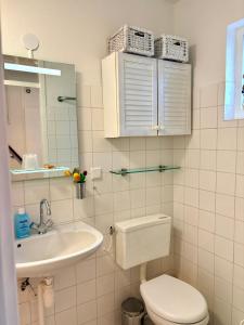 a white bathroom with a toilet and a sink at De Korre 10 in Callantsoog +10 photos