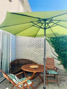 a table and chairs under a green umbrella on a patio at De Korre 10 in Callantsoog