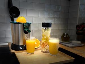 two glasses of orange juice and a juicer on a cutting board at Casa Carlini in Getxo