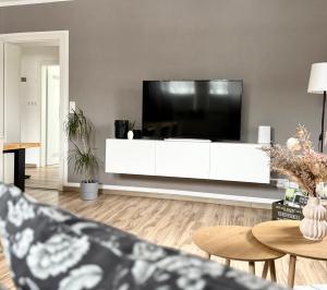 a living room with a large tv on a white cabinet at City Flair by Zirwick Apartment in Weiden