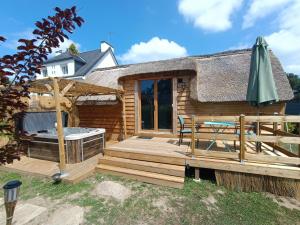 a deck with a hot tub and an umbrella at Tiny Chaumière - Escapade Romantique - Chaumière et Jacuzzi Privatif proche Pont-Aven in Riec-sur-Bélon