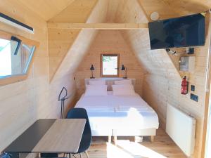 a bedroom in a tiny house with a bed and a table at Tiny Chaumière - Escapade Romantique - Chaumière et Jacuzzi Privatif proche Pont-Aven in Riec-sur-Bélon