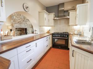 a kitchen with white cabinets and a stone fireplace at Tyddyn Goronwy in Dyffryn