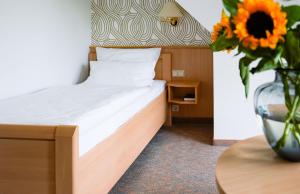 a bedroom with a bed and a vase with a sunflower at Hotel Marschall Duroc in Görlitz +70 photos