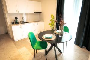 a kitchen with a table and two green chairs at RMR Luxury Apartaments in Timişoara