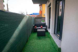 a balcony with a couch and a table on a green floor at RMR Luxury Apartaments in Timişoara