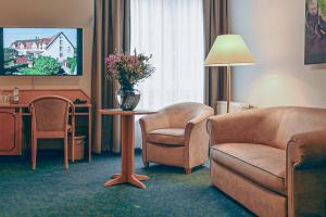 a hotel room with a couch and a chair and a table at Hotel Marschall Duroc in Görlitz