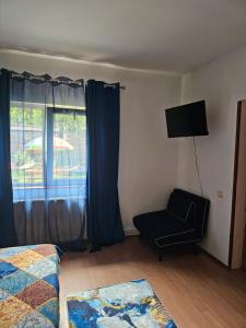 a bedroom with a bed and a chair and a window at Villa Foisor in Buşteni