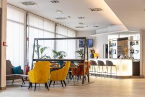 a dining room with a table and yellow chairs at LVG Hotel Collection - Cavour in Novara