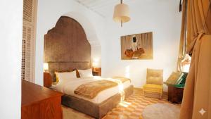 a bedroom with a bed and a desk and a guitar at Riad Chama in Essaouira