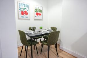 a dining room with a black table and green chairs at Cambridge Apartment in Glasgow