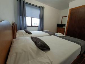 two beds in a hotel room with a window at Faial Oceanfront Getaway AL in Horta