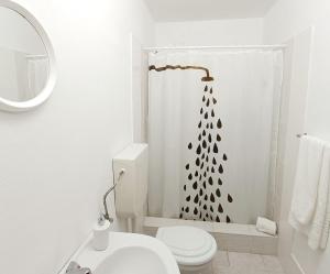 a white bathroom with a toilet and a shower curtain at Faial Oceanfront Getaway AL in Horta