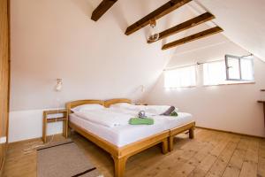 a bedroom with a bed with white sheets and wooden floors at Ferma de Biodiversitate COBOR in Cobor