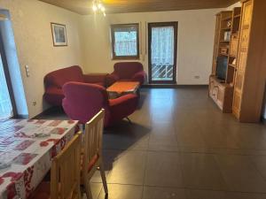 a living room with red couches and a tv at Panoramaferienwohnungen Stemler in Eulenbis