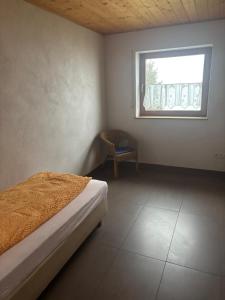 a bedroom with a bed and a window and a chair at Panoramaferienwohnungen Stemler in Eulenbis