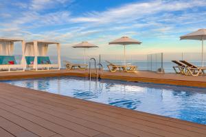 a swimming pool on a deck with chairs and umbrellas at Aluasun Lago Rojo - Adults recommended in Torremolinos