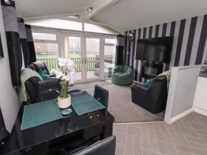 a living room with chairs and a table and a television at Harper's Hideaway in Morpeth