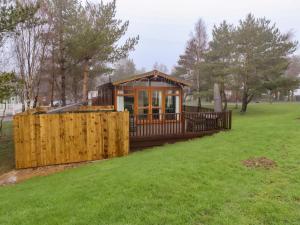 a small house in a park with a fence at Harper's Hideaway in Morpeth