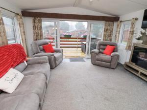 a living room with a couch and two chairs and a television at Chloe's Cabin in Morpeth