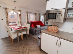 a kitchen and living room with a table and a microwave at Chloe's Cabin in Morpeth