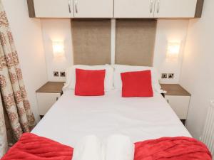 a bedroom with a white bed with red pillows at Chloe's Cabin in Morpeth