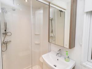 a white bathroom with a sink and a shower at Chloe's Cabin in Morpeth +20 photos