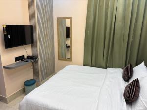 a bedroom with a white bed and a television at Hotel Maple Lawn in Guwahati