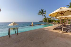 a swimming pool with chairs and umbrellas next to the ocean at "Infinity Blue", Private Beach! in Sosúa