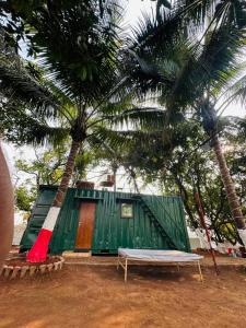 a green building with a bench next to a palm tree at TOMS' Cabin Farmhouse in Chauk
