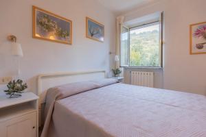 a white bedroom with a bed and a window at Appartamenti Belvedere by ElbaSummer in Lacona