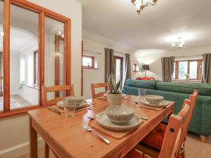 a dining room with a wooden table and a green couch at The Pantiles in Norwich